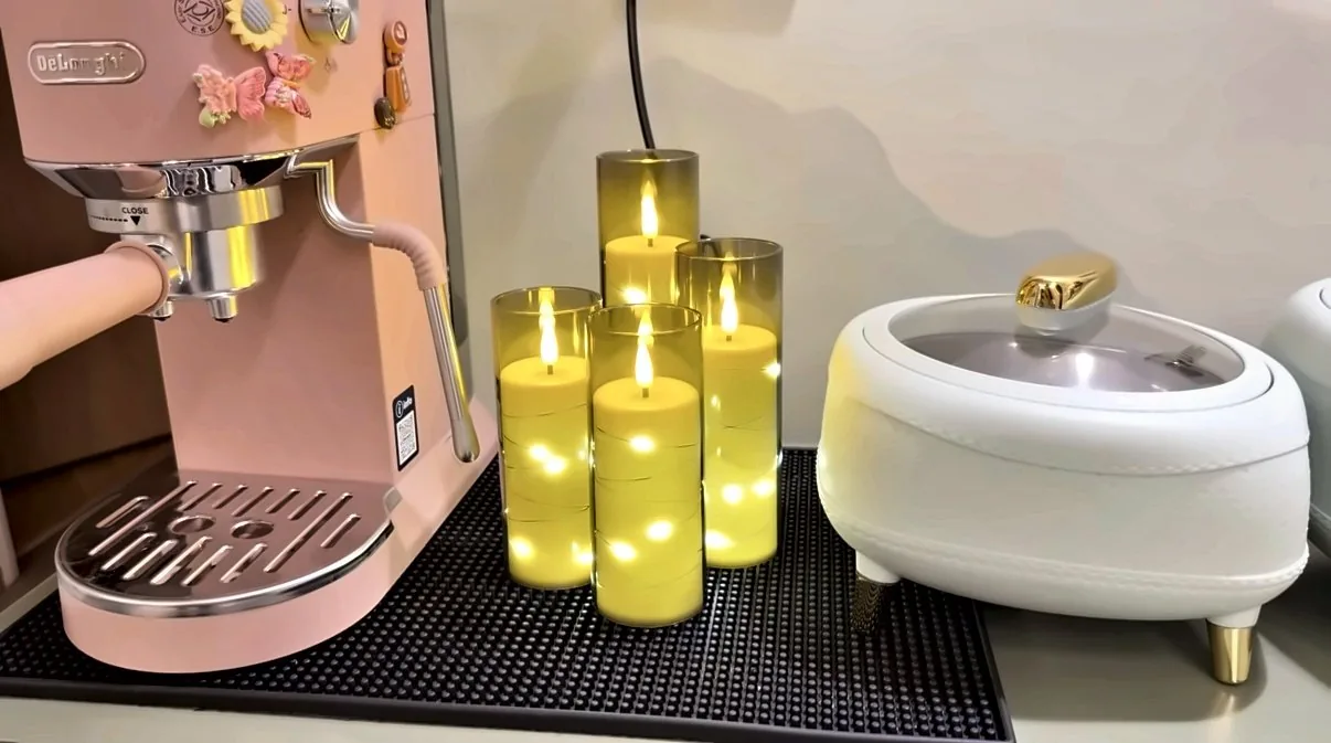 Pink espresso machine with flickering LED pillar candles on a black bar mat