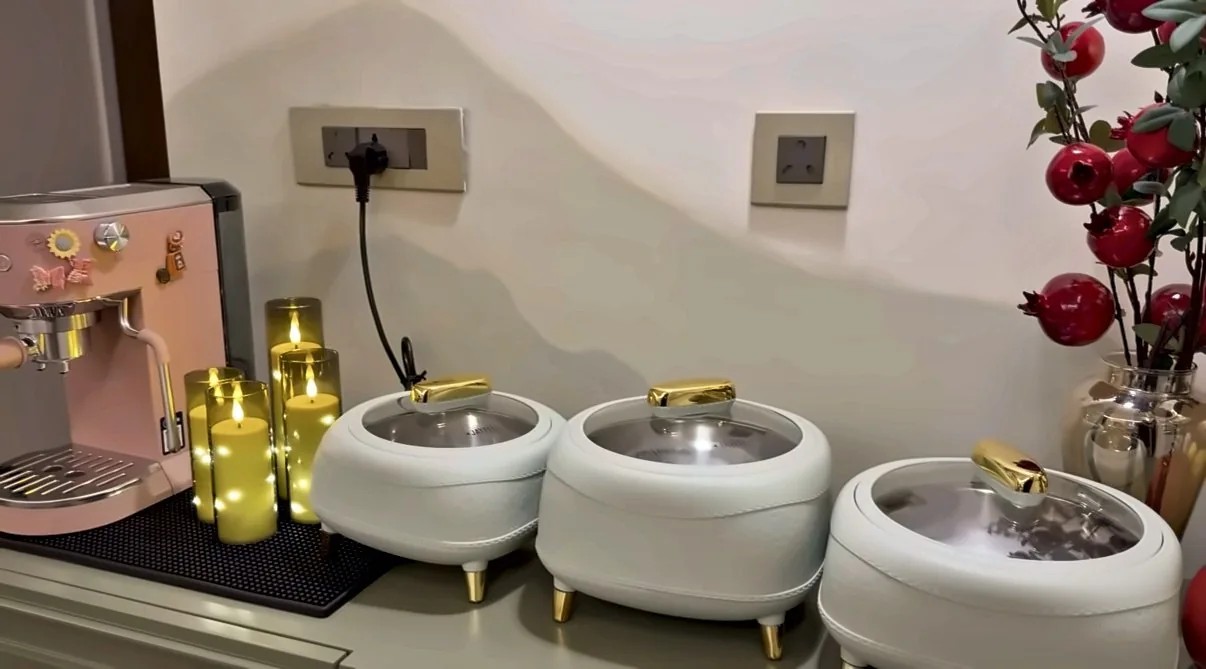 Three white quilted serving dishes with gold handles and gold legs lined up on the console