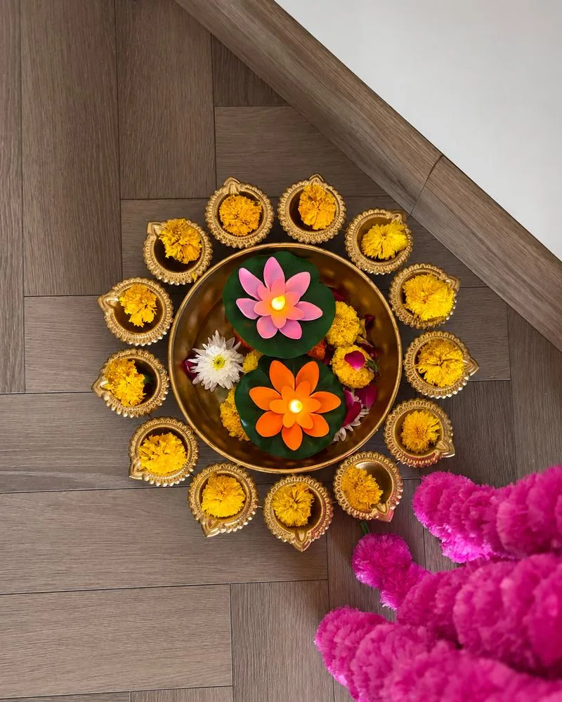 Brass urli ringed with marigold-filled diyas and floating lotus candles