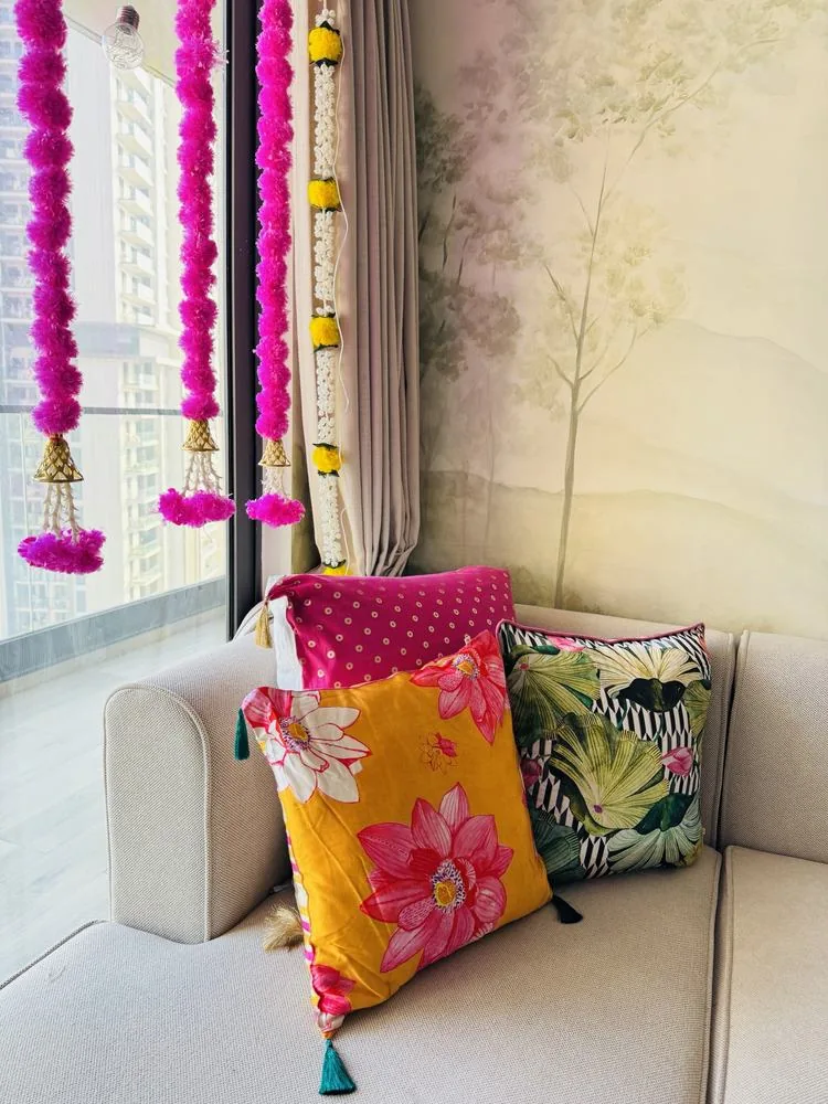 Bright cushions on the sofa with pink and marigold hangings at the window, by day