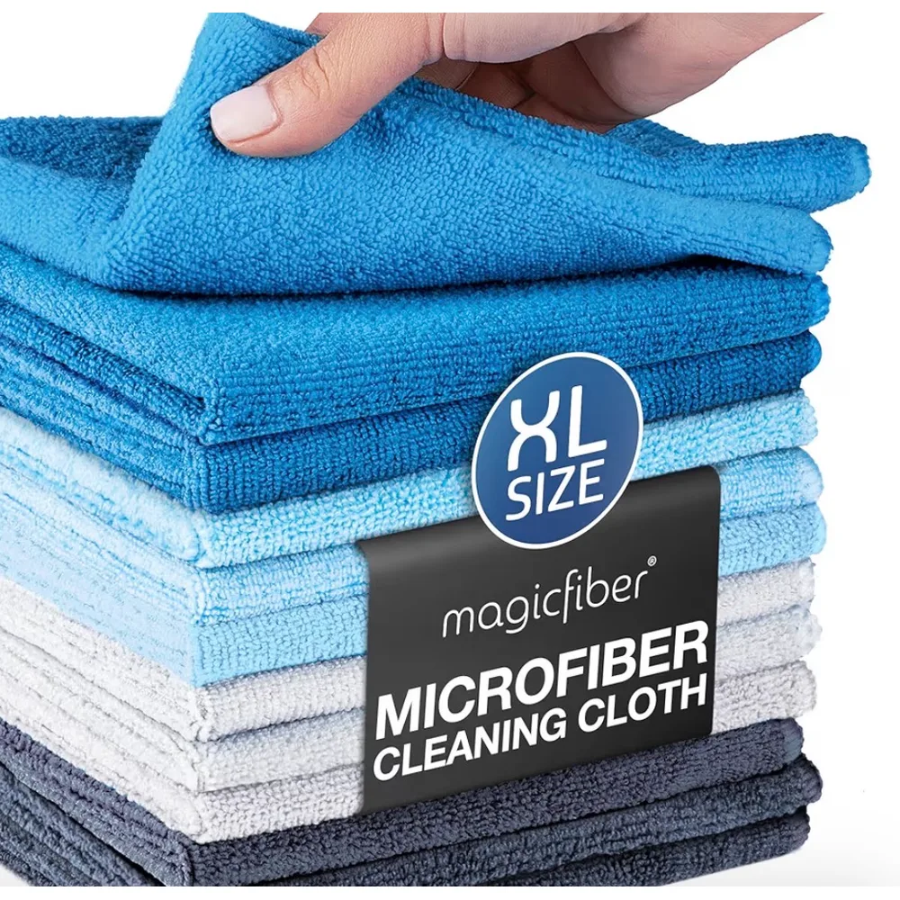 A stack of MagicFiber XL microfiber cloths in blues, white and grey, one corner lifted by hand