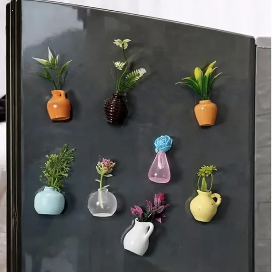 Tiny vase magnets holding faux flowers and plants on a black fridge door
