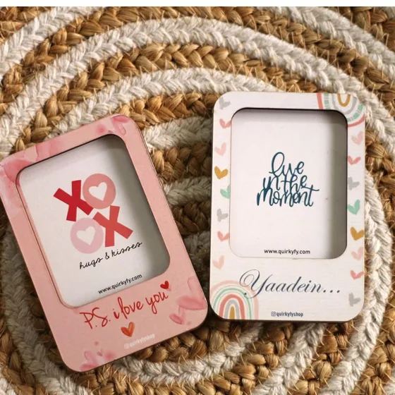 Two pastel photo frame magnets printed with XOXO and hearts, laid on a woven mat