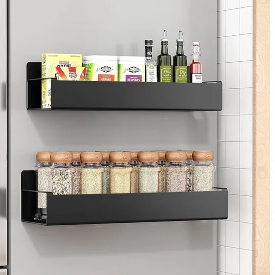 Two black magnetic spice racks on the side of a fridge, holding jars and bottles