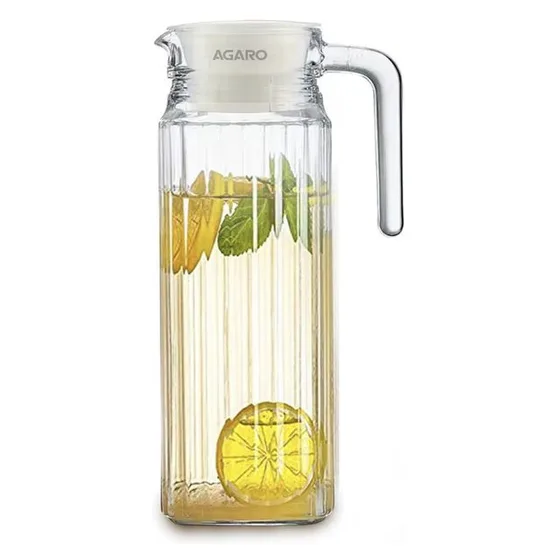 A fluted glass jug with a white lid and handle, holding lemon water