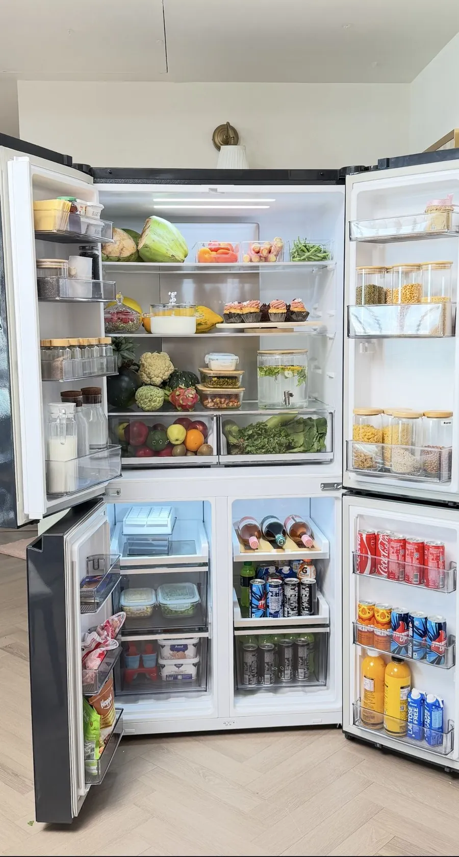 An organised four-door fridge with clear bins, glass jars and jugs
