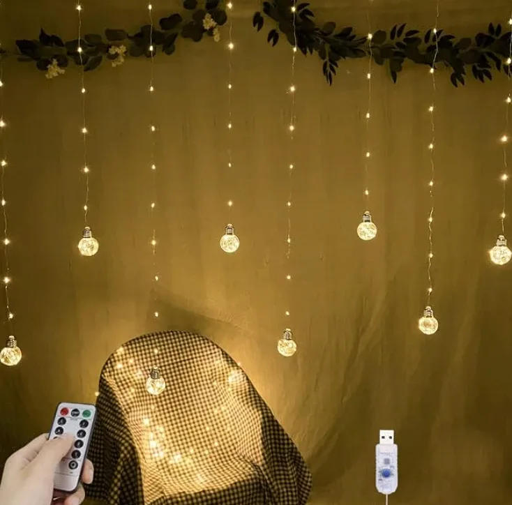 A curtain of fine wires hung with small glass globe bulbs against a dark wall