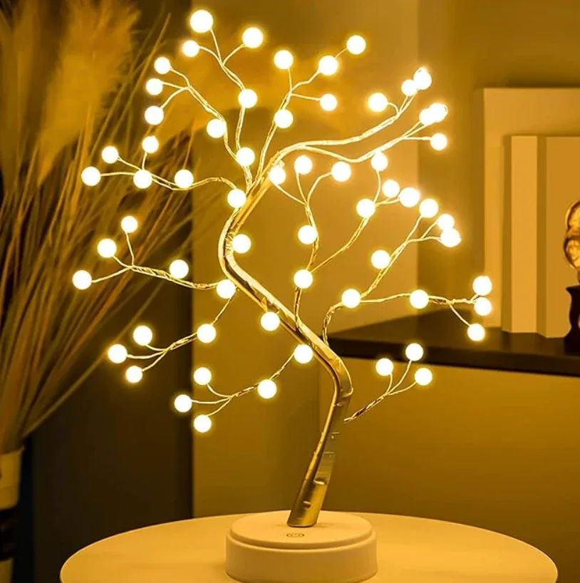A tabletop tree lamp with white globe bulbs on wire branches, lit on a side table