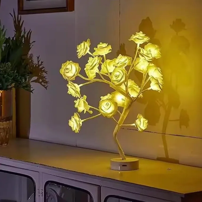 A tree lamp made of lit fabric roses, casting its shadow up a wall
