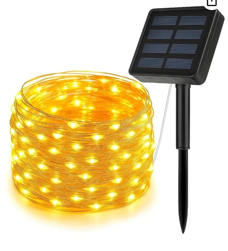 A coil of warm copper-wire fairy lights with a stake-mounted solar panel