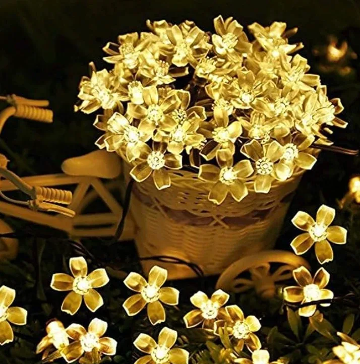 Blossom-shaped bulbs on a fine wire, spilling out of a basket in a garden at night