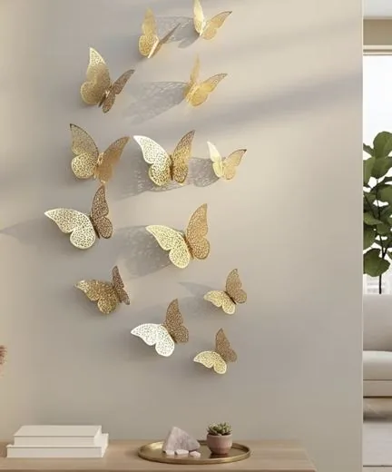 Gold filigree butterfly wall stickers in three sizes, flying up a beige wall