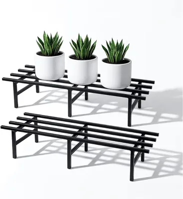 Two low black horizontal metal pot stands holding white pots