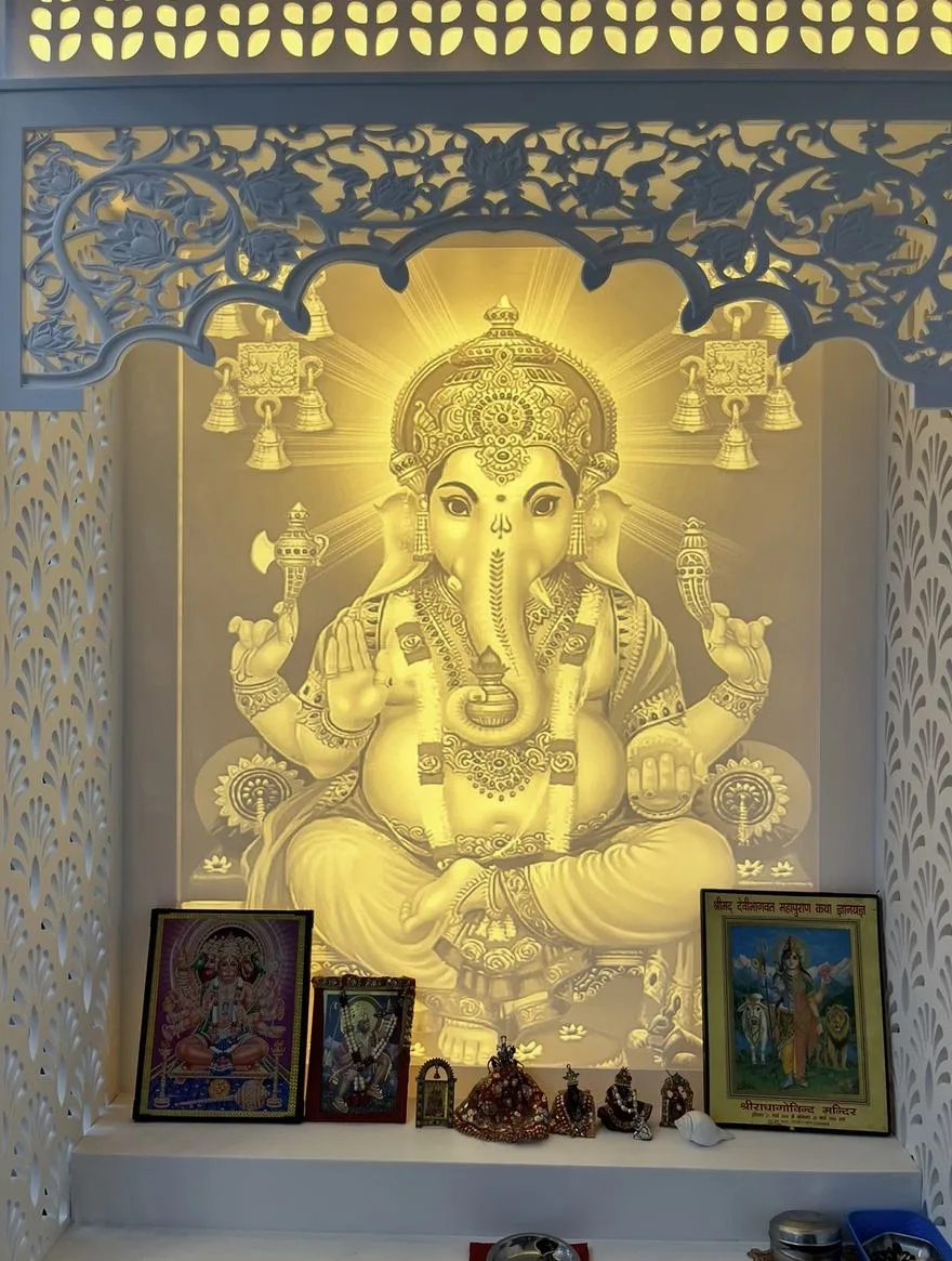 Backlit Ganesh panel glowing behind a carved jaali arch and pierced side panels
